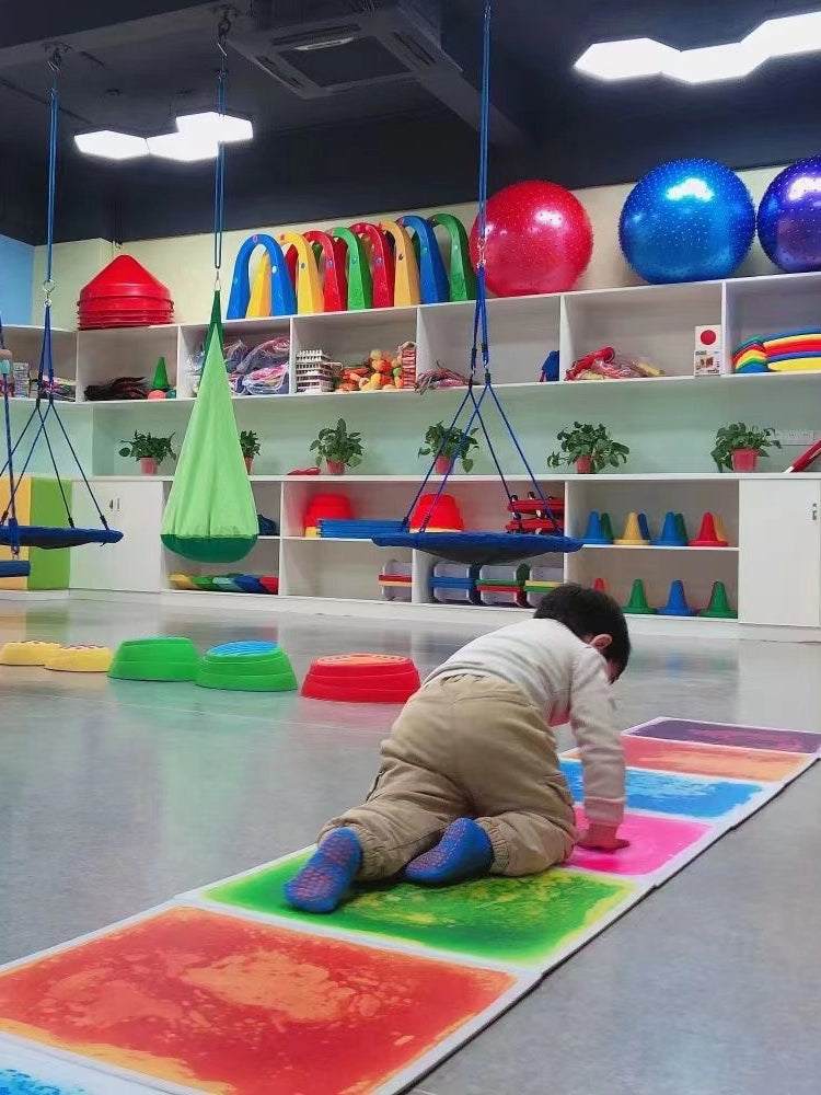 Child crawling on vibrant Early Education Sensory Liquid Tile mat in colorful playroom, enhancing sensory development.
