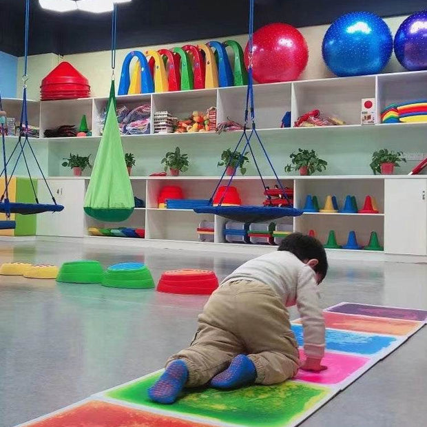 Child crawling on vibrant Early Education Sensory Liquid Tile mat in colorful playroom, enhancing sensory development.
