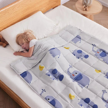 Kid peacefully sleeping under Anfie sensory weighted blanket with elephant designs on a bed.